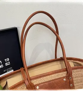 Detail of straw woven tote with brown leather handles and reinforced metal rivets