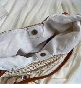 Detail of woven straw bucket bag showing bronze magnetic snaps and canvas lining