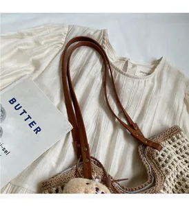Detail of hand-woven tote bag with brown leather handles and a cute plush bear charm