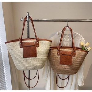 Detail of woven straw tote bags featuring leather handles and decorative pockets