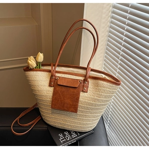Detail of hand-woven straw tote with premium brown leather trim and tulip accessory