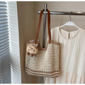 Close-up of woven bucket bag featuring hollow mesh texture and brown faux leather handles