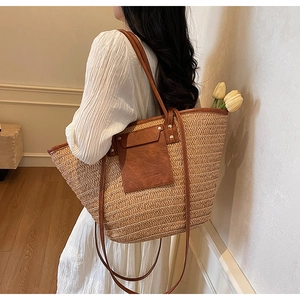 Detail of woven straw tote bag with brown leather handles and decorative tulips
