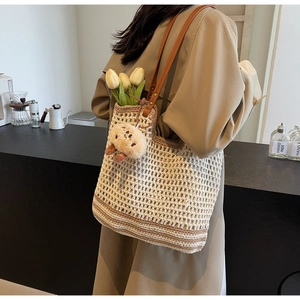 Close-up of contrast woven tote bag texture with brown leather strap and plush charm