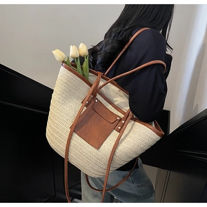 Detail showing the straw tote bag with brown leather trim and shoulder straps