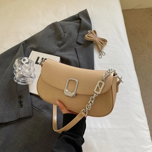 Chic beige soft leather moon bag with silver chain strap on a gray blazer suit