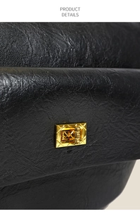 Détail d'un sac en cuir noir grainé avec un fermoir rotatif doré à texture quadrillée