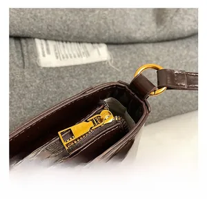 Detailed macro view of dark brown leather saddle bag with premium gold metal zippers