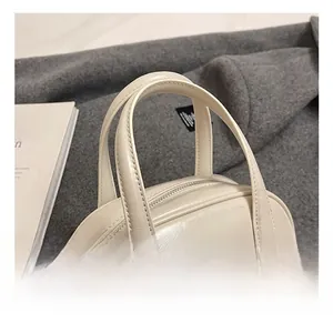 Close-up of beige leather bowling bag with reinforced handles and silver metal hardware