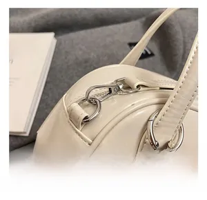 Close-up of silver metal hook and strap connector on a cream bowling shoulder bag