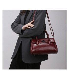 Detail of burgundy leather handbag showing the woven handle and metal twist lock