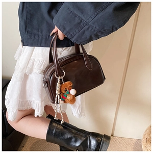 Detail of vintage dark brown bowling bag with a cute plush bear charm and glossy finish