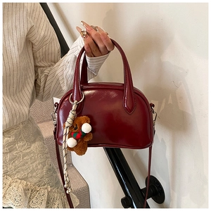 Glossy burgundy patent leather bowling bag detail with a cute plush bear charm