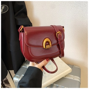 Close-up of vintage burgundy saddle bag with elegant U-shaped gold hardware buckle