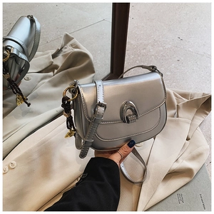 Detail of silver metallic saddle bag on beige suit showing texture and buckle