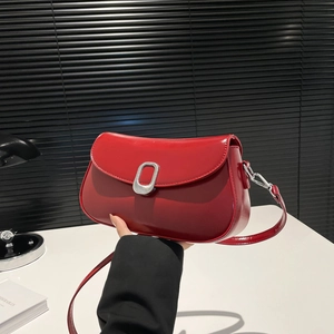 Glossy red faux leather crossbody bag with silver buckle and curved flap for women