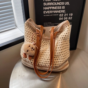 Retro beige woven crochet bucket bag with brown leather handles and plush charm