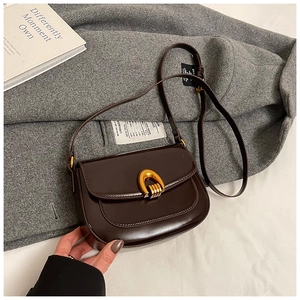 Detail of dark brown saddle bag with gold horseshoe buckle on wool coat background