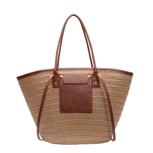Straw tote bag with brown faux leather trim and drawstring design for summer vacations