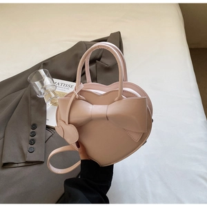 Détail d'un sac à main rose en forme de cœur avec un grand nœud et une poignée chic