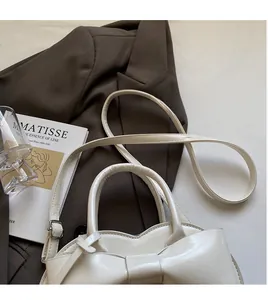 Détail d'un sac à main blanc en similicuir avec nœud décoratif et bandoulière réglable