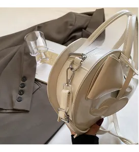 Détail latéral d'un sac à bandoulière rond crème avec des ferrures en argent chic