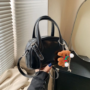 Glossy black bowling handbag with teddy bear charm and adjustable shoulder strap
