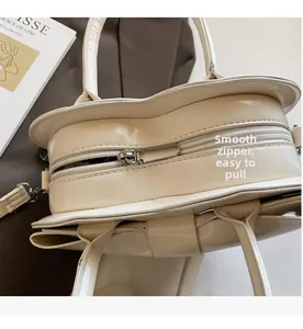 Gros plan sur la fermeture éclair argentée fluide d'un sac à main beige en forme de cœur