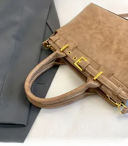 Dettaglio della borsa tote vintage in pelle marrone con manico e fibbie dorate
