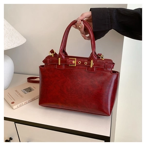 Dettaglio di una borsa tote rosso vino vintage con finitura lucida e fibbie dorate