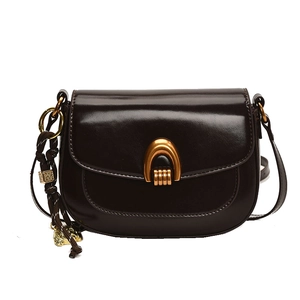 Deep brown leather saddle bag with golden arch buckle and woven strap on white background