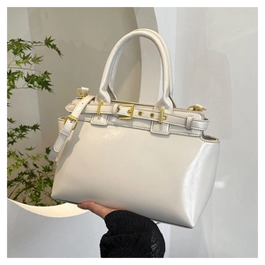 Dettaglio della borsa tote in vernice bianco crema con fibbie dorate e tracolla