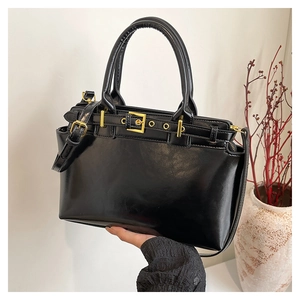 Dettaglio della borsa tote in pelle lucida nera con fibbia dorata e manici