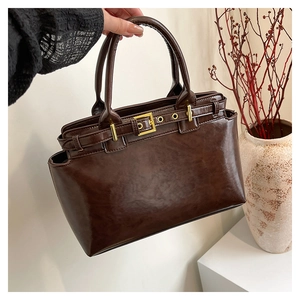 Dettaglio della borsa vintage marrone scuro con texture lucida e fibbie in metallo oro