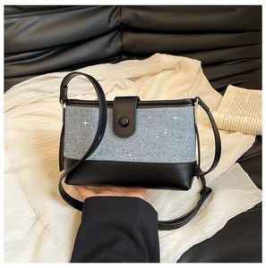 Close-up of contrast color small square bag with blue denim texture and black leather