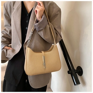Gros plan du sac beige avec texture tressée, fermoir métallique argenté et bandoulière
