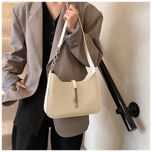 Détail du sac sous le bras tissé crème avec boucle argentée et chaîne sur la bandoulière