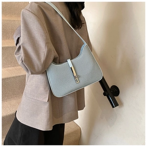 Détail de la texture tissée et de la boucle dorée d'un sac sous le bras bleu en croissant