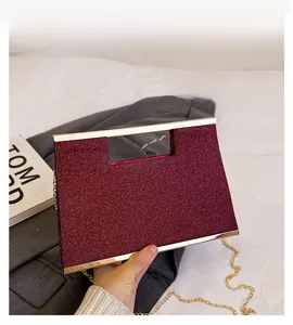 Dettaglio della pochette bordeaux con paillettes, manico in metallo dorato e catena