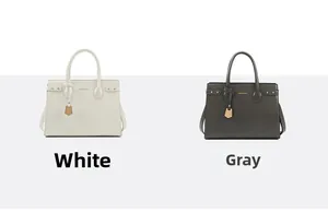 Detail view of structured leather handbags in white and gray with decorative side straps