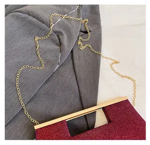 Dettaglio della pochette da sera rosso scuro glitterata con montatura in oro e catena