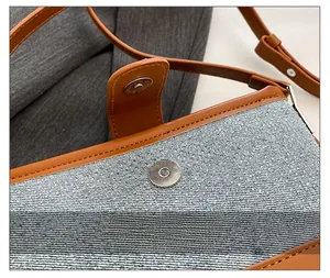 Detail of magnetic button closure on contrast stitching leather shoulder bag
