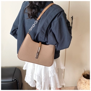 Détail d'un sac à bandoulière marron tressé avec boucle en métal argenté sur un mannequin