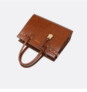Detailed view of brown faux leather tote with golden rivets and fashion logo