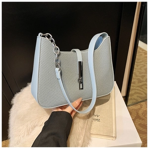 Détail du sac baguette bleu clair tressé avec bandoulière chaîne argentée et fermoir métal