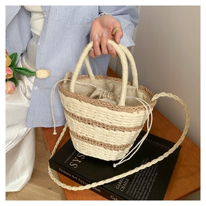 Détail du sac seau bicolore en paille tressée avec double poignée et pochette intérieure
