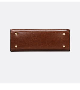 Detail view of brown leather tote base featuring four protective gold metal feet studs