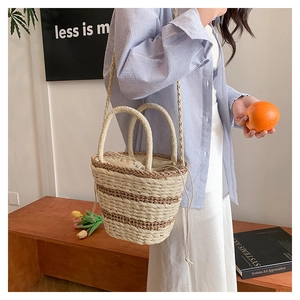 Détail du sac seau en paille tissé main avec motif rayé et fermeture par cordon en tissu