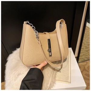 Gros plan d'un sac à main beige tissé avec fermoir en métal argenté et bandoulière