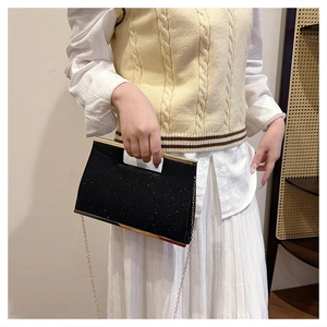 Dettaglio della pochette da sera nera glitterata con bordo dorato e catena